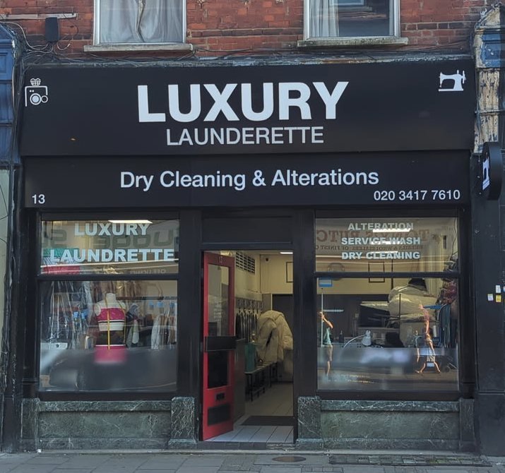 The Luxury Launderette shopfront at 13 Crouch Hill, with its black sign and red door